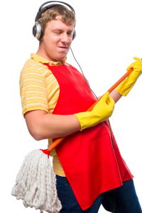 emotional man housewife with a mop in headphones on a white background